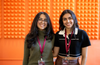 Spur co-founders Anushka Nijhawan and Sneha Sivakumar at Y Combinator, standing in front of an orange acoustic wall.