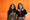 Spur co-founders Anushka Nijhawan and Sneha Sivakumar at Y Combinator, standing in front of an orange acoustic wall.