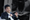 Dr. Hon Weng Chong, CEO of Cortical Labs, speaking at a conference, overlaid with an image of neuron cell examination under a microscope.